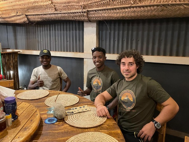 A hiker celebrating with Kilimanjaro guides in Moshi after returning from the mountain, smiling and happy after a successful climb